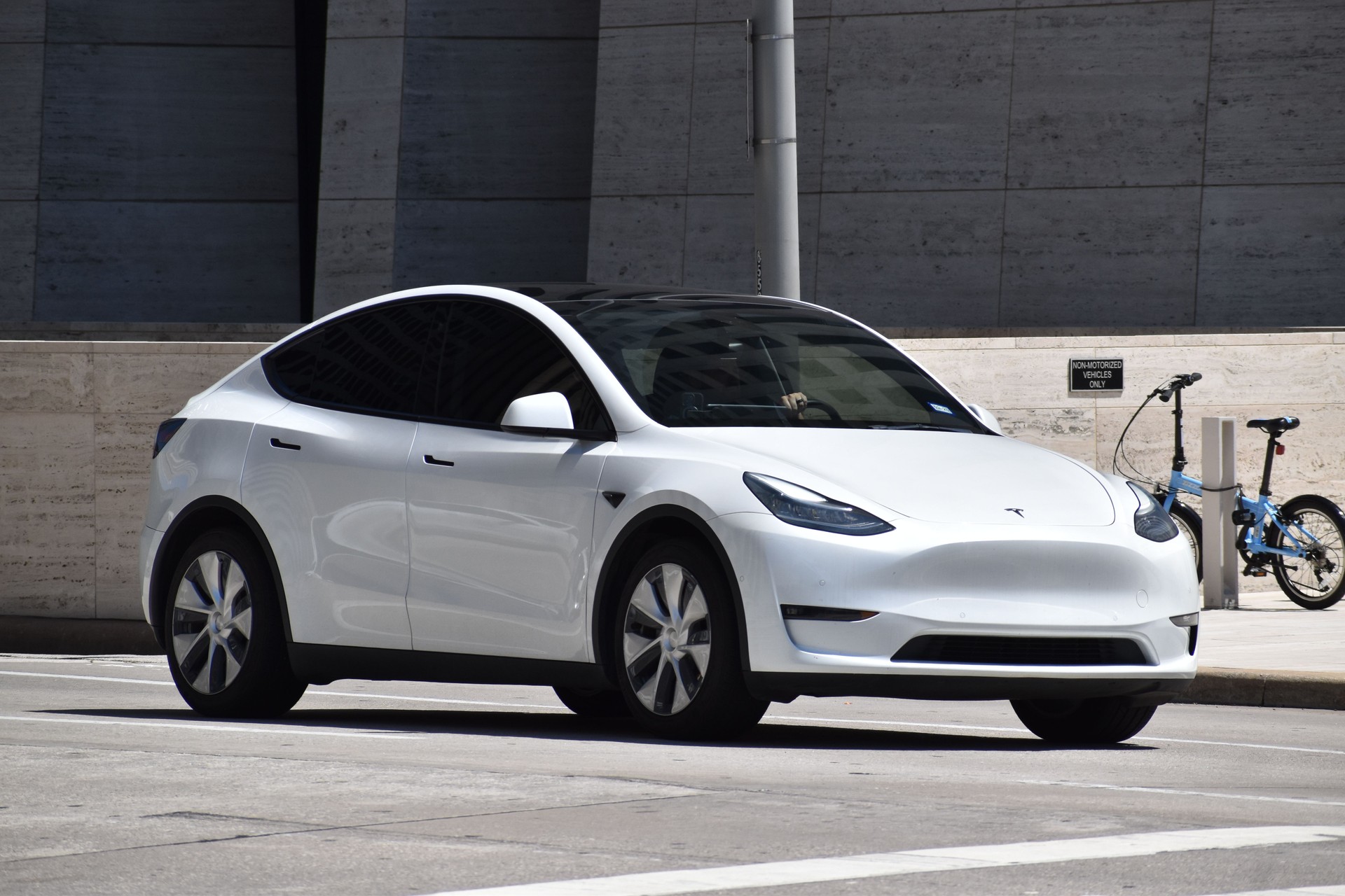 A portrait of a white colored Tesla Model 3 cruising in a downtown district